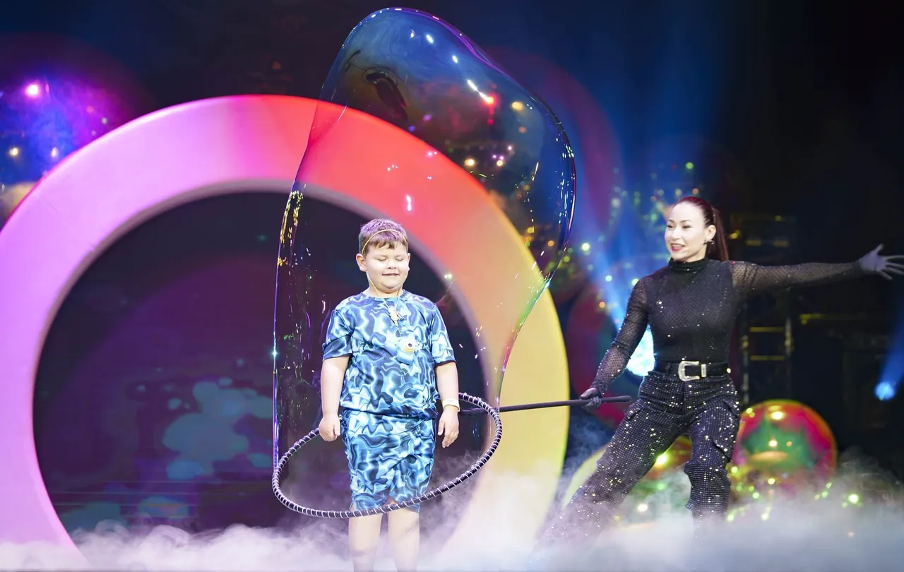 Children watching a large rainbow-colored bubble at The Gazillion Bubble Show